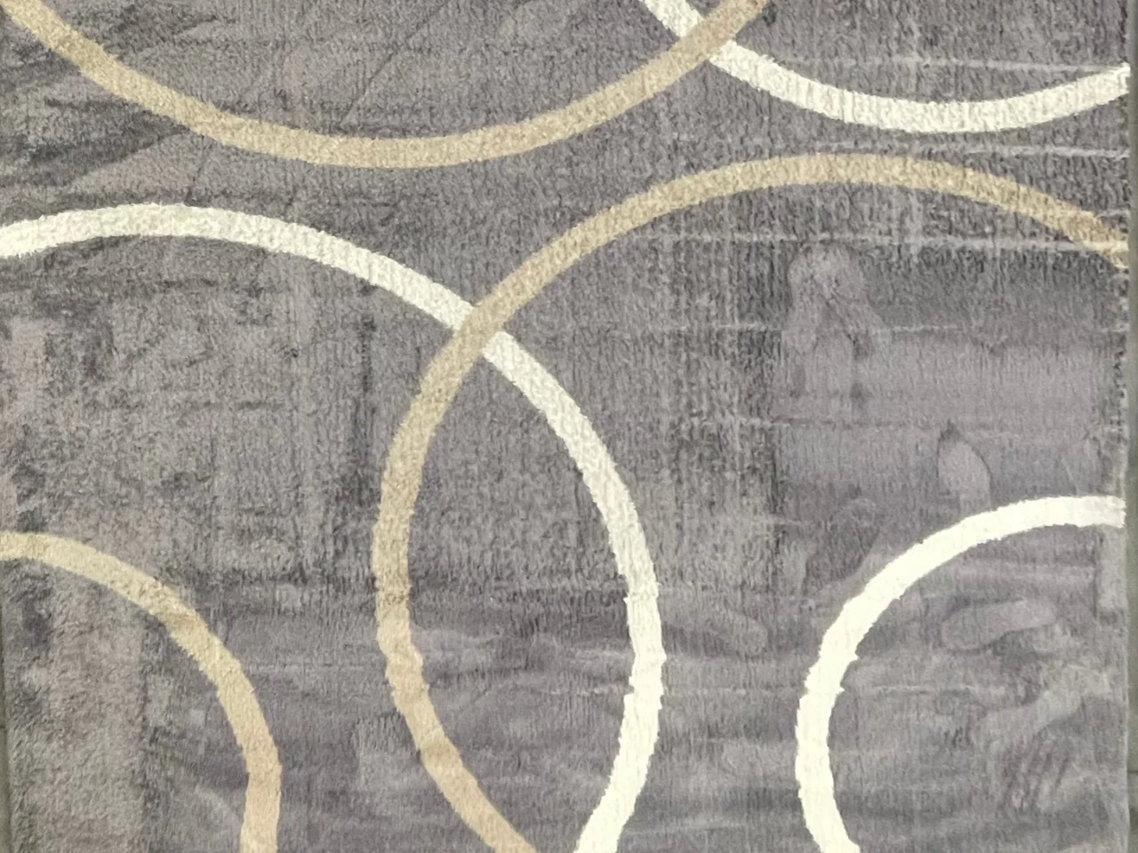 Before: close-up of the modern gray wool rug with cream and beige arcs, showing a matted, uneven and soiled pile