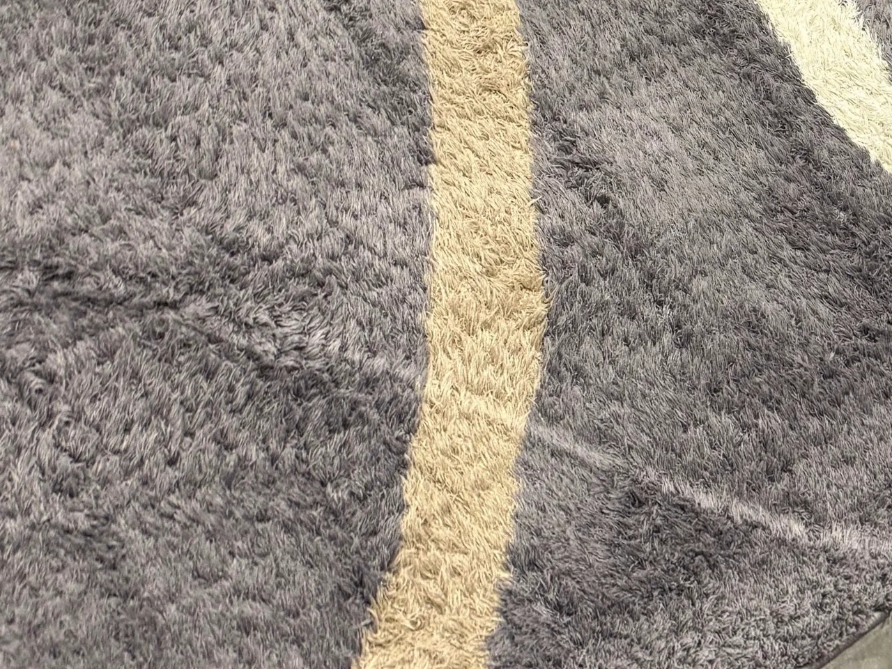 Close-up of the matted pile of the modern gray wool rug during cleaning