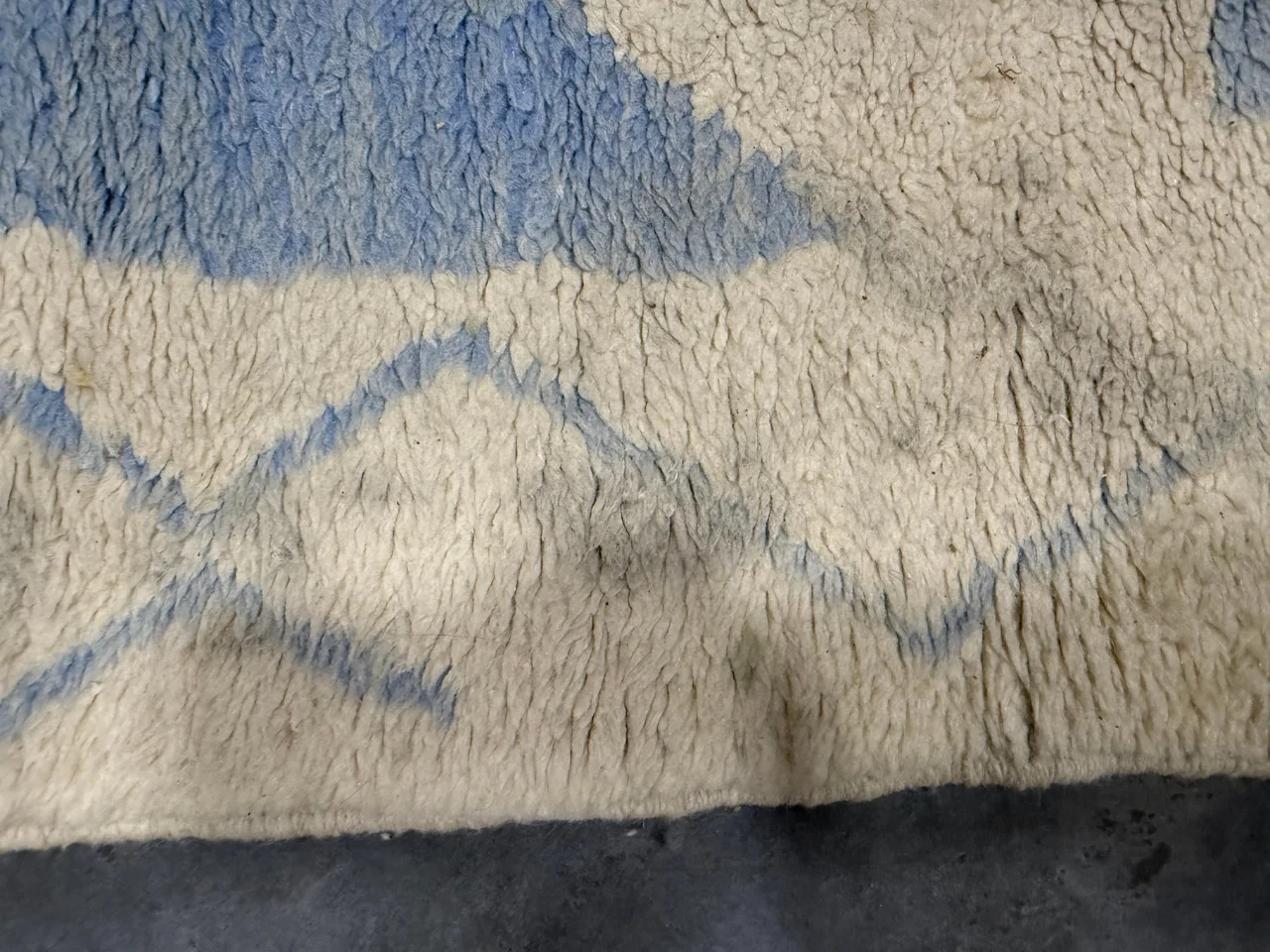 Arrival photo showing stains on the natural wool rug