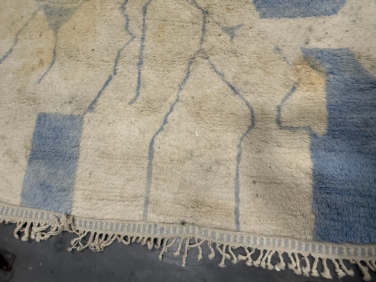 The soiled fringe of the natural wool rug before cleaning
