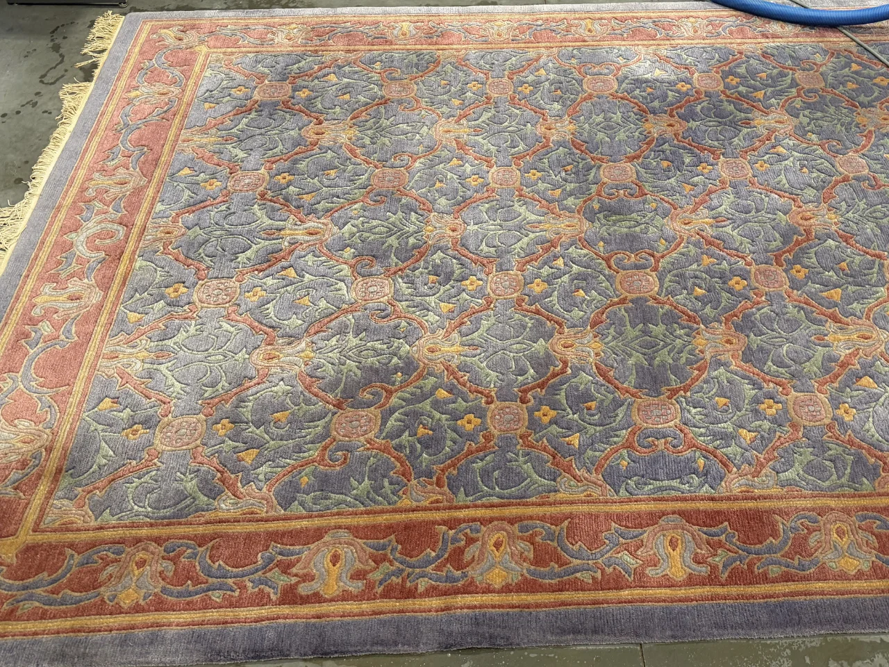 Before: Oriental-style wool rug with a blue-gray field and rust-red borders, dulled by a year of dust and dirt, from a Brush Prairie, WA home