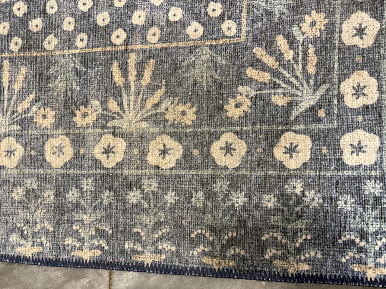 Inspection photo showing discoloration in the blue and ivory wool-blend rug